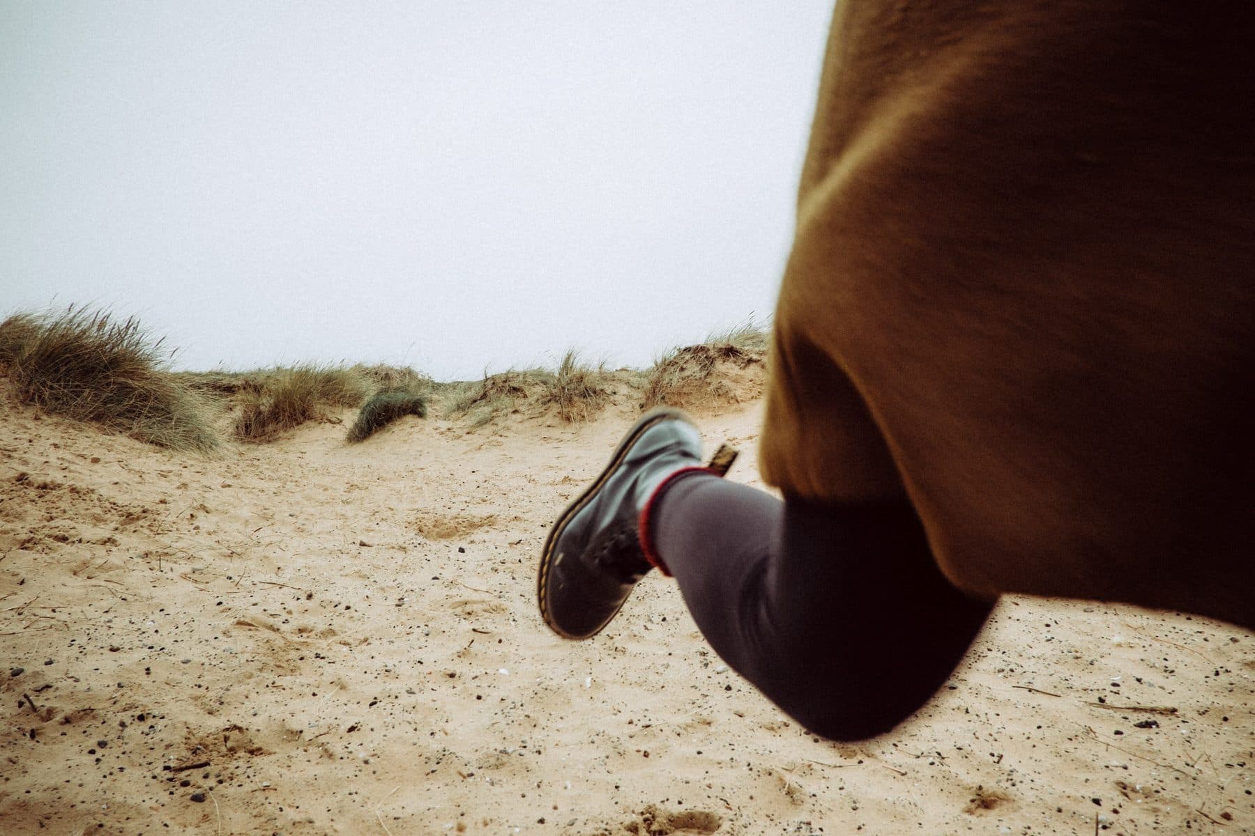 A runner mid-stride on a sand dune, legs only